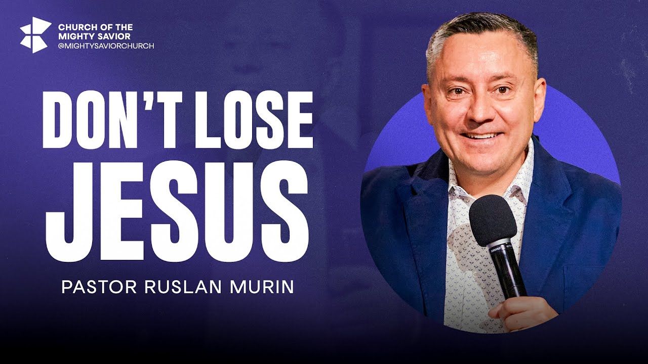 Ruslan Murin in a blue jacket, smiling and holding a microphone.