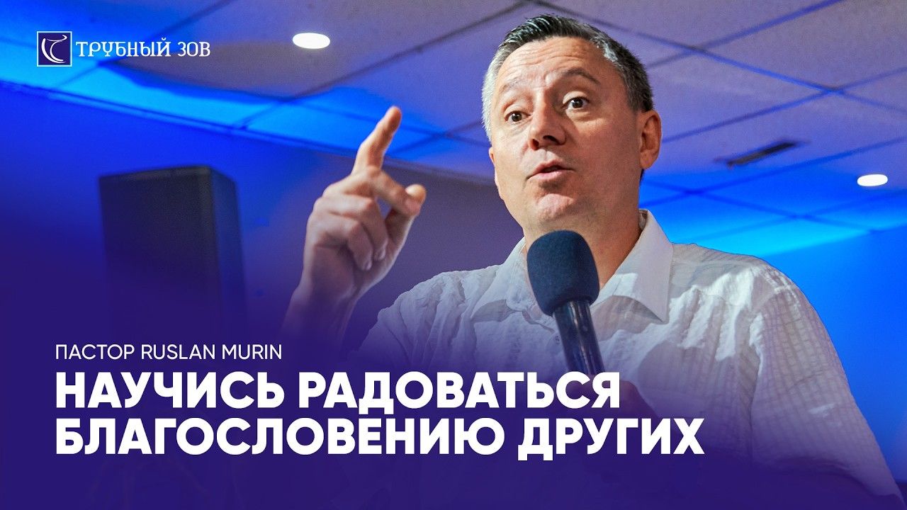 Pastor Ruslan Murin preaching into a microphone with one hand raised.