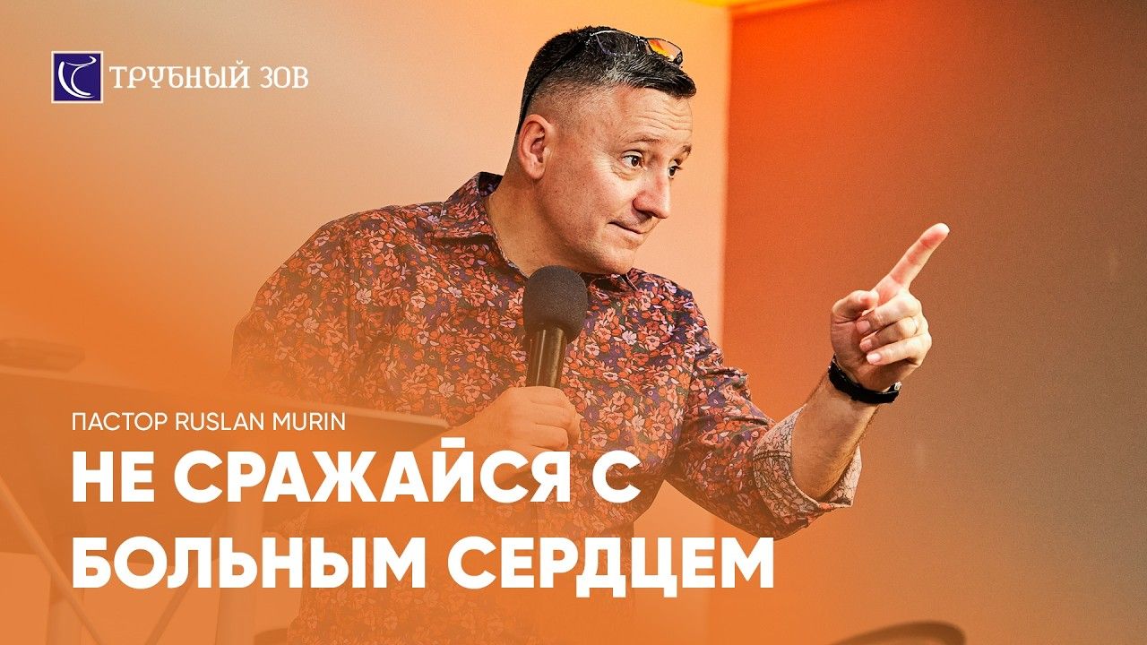 Pastor Ruslan Murin holding a microphone against an orange background.