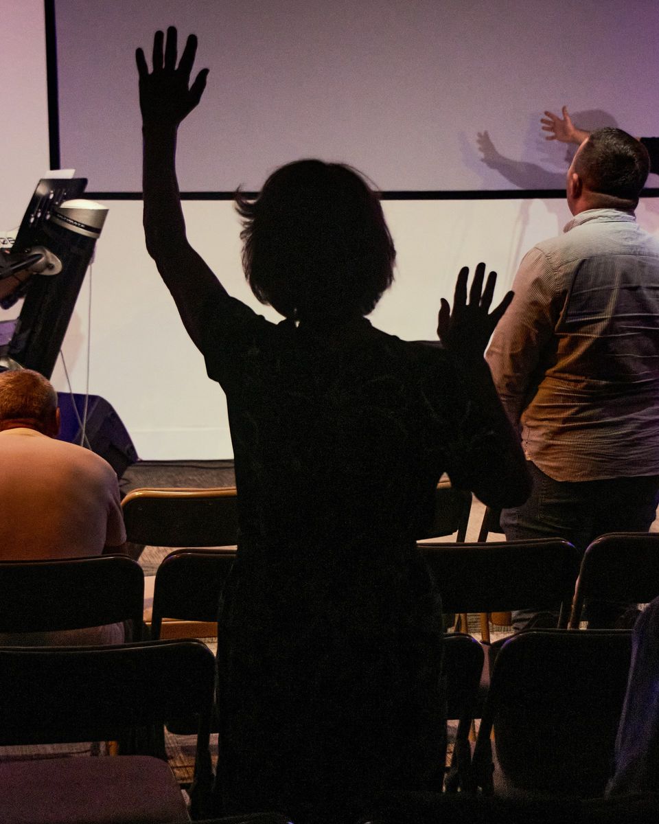 People standing with raised hands during worship