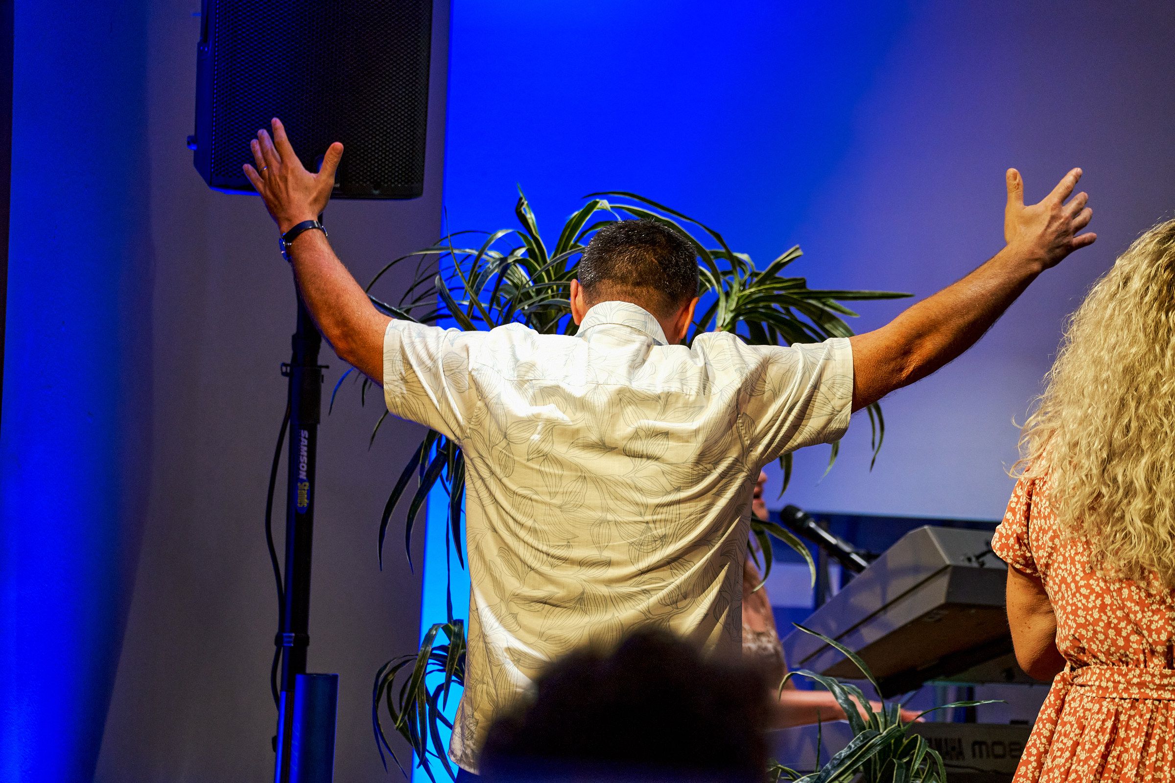A man seen from behind with his arms outstretched during worship