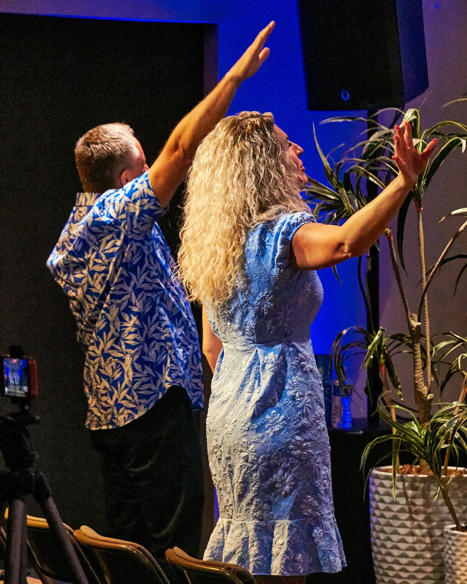 A man and a woman with raised arms, seen from behind