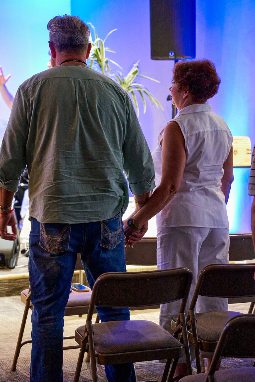 Two people standing with their backs to the camera, holding hands