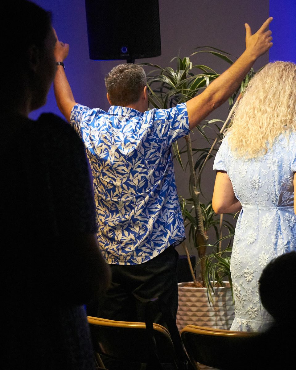 A man with both arms raised and a woman beside him, seen from behind.