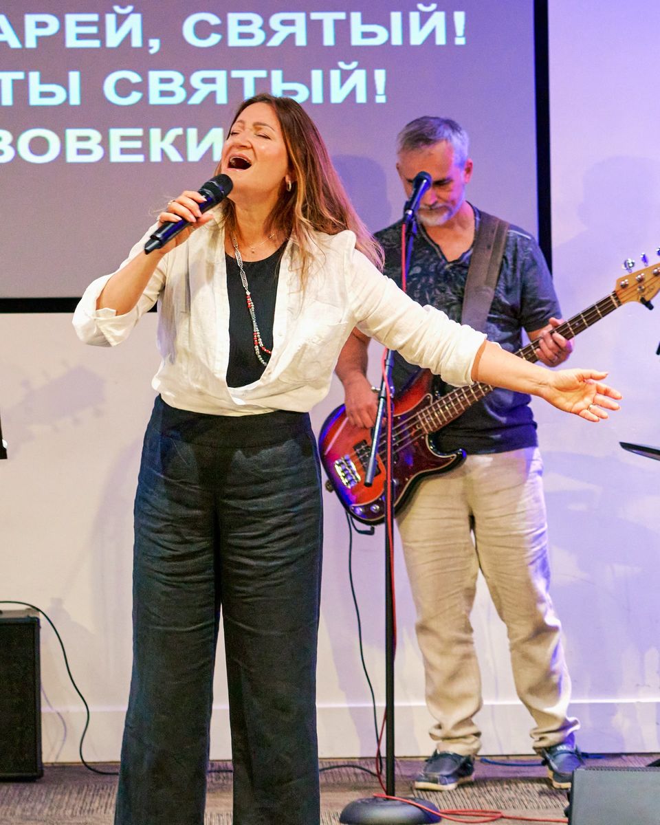 A vocalist singing with open arms, a bassist behind her